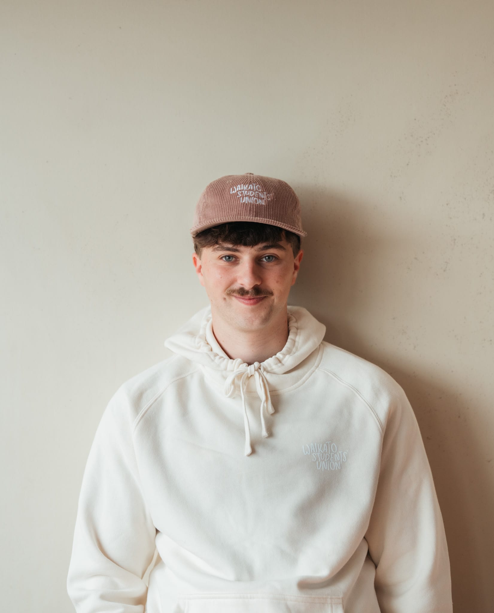 Seamus in the cream hoodie and cap, hands in pockets