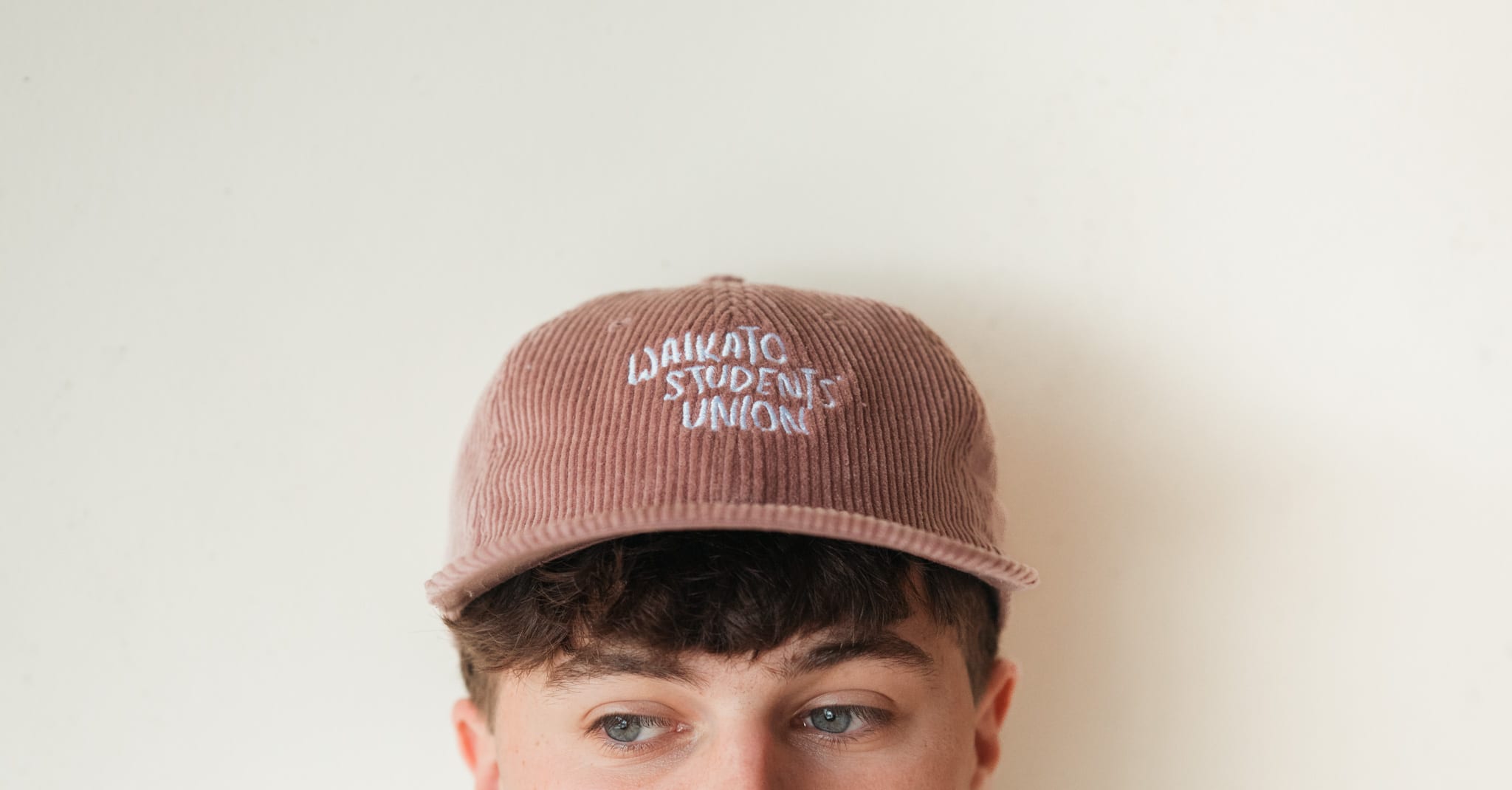 Seamus peering from under the brim of the pink corduroy union cap